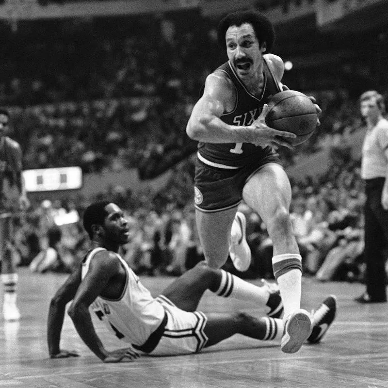 Henry Bibby leaps over Nate Archibald of Boston Celtics