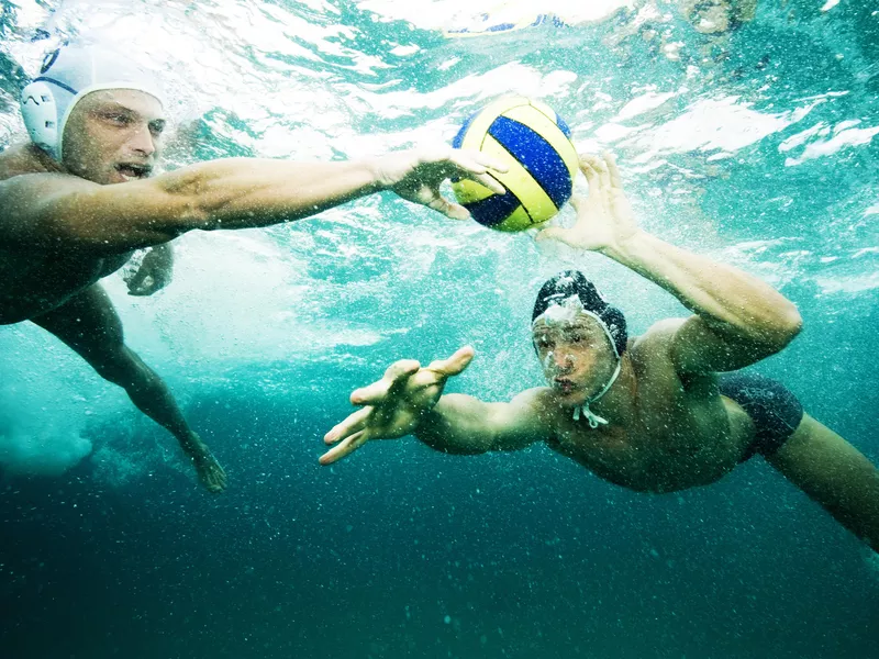 Men fighting for ball under water