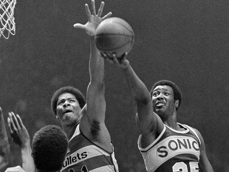 Washington Bullets' Wes Unseld reaches to block shot by Seattle Supersonics' Paul Silas