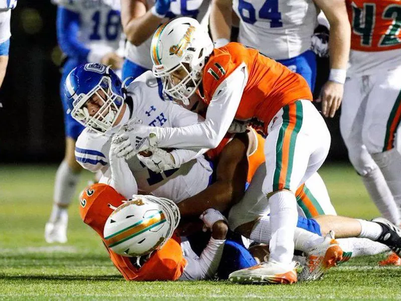 Frederick Douglass High School football players (in orange) make a tackle