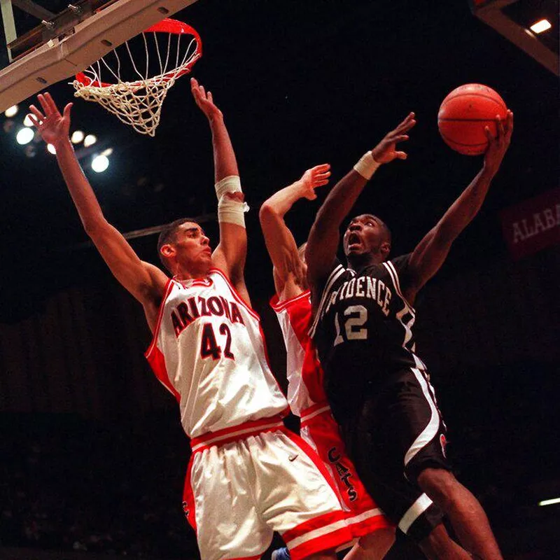 Providence's God Shammgod (12) flies to the hoop against Arizona's A.J. Bramlett (42)