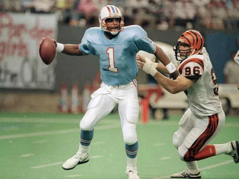 Houston Oiler quarterback Warren Moon is pressured by Cincinnati Bengal Natu Tautagaloa