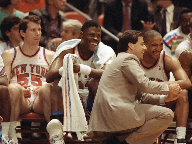 Kiki Vandeweghe, Patrick Ewing, and Mark Jackson laugh on bench