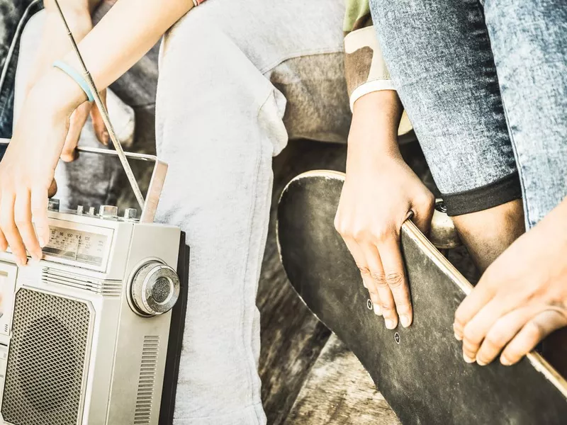 Friends holding a vintage skateboard and radio