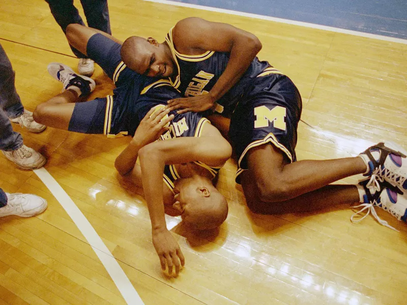 Juwan Howard and Jalen Rose rolling around in celebration