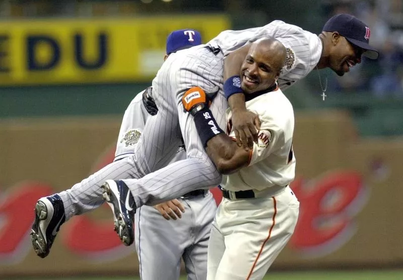 Barry Bonds of the San Francisco Giants picks up Torii Hunter of the Minnesota Twins after he robbed Bonds