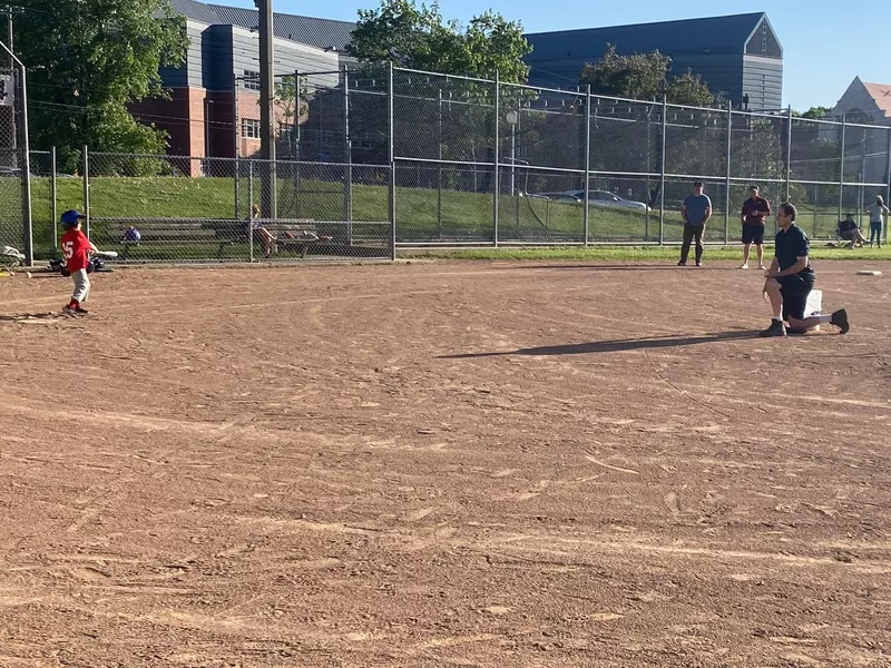 Coach pitching to youth batter