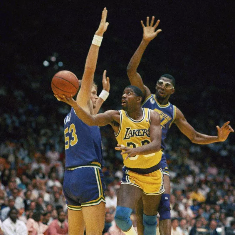 Magic Johnson drives between Utah Jazz players