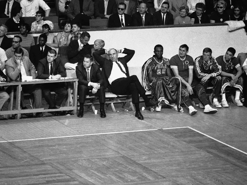 Philadelphia 76ers coach Alex Hannum relaxes while watching his team