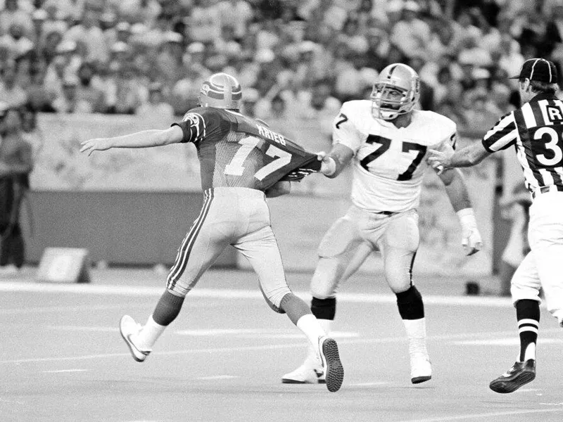 Los Angeles Raiders defensive end Lyle Alzado roughs up Seattle Seahawks quarterback Dave Krieg