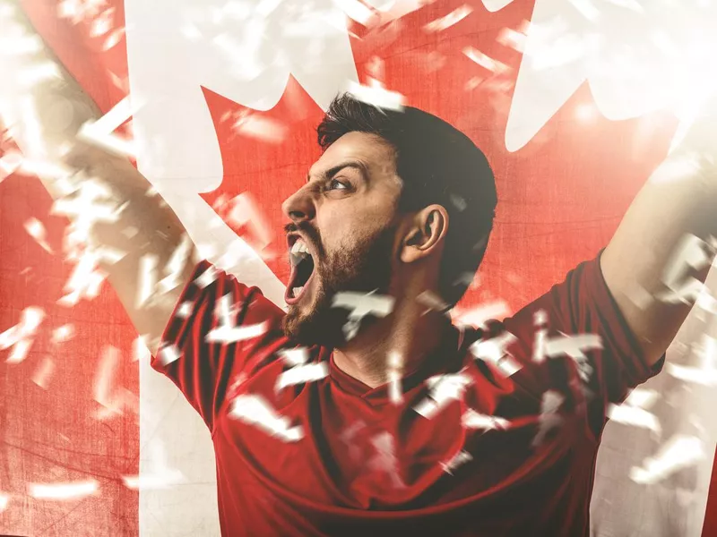 Football fan celebrating and holding the flag of Canada