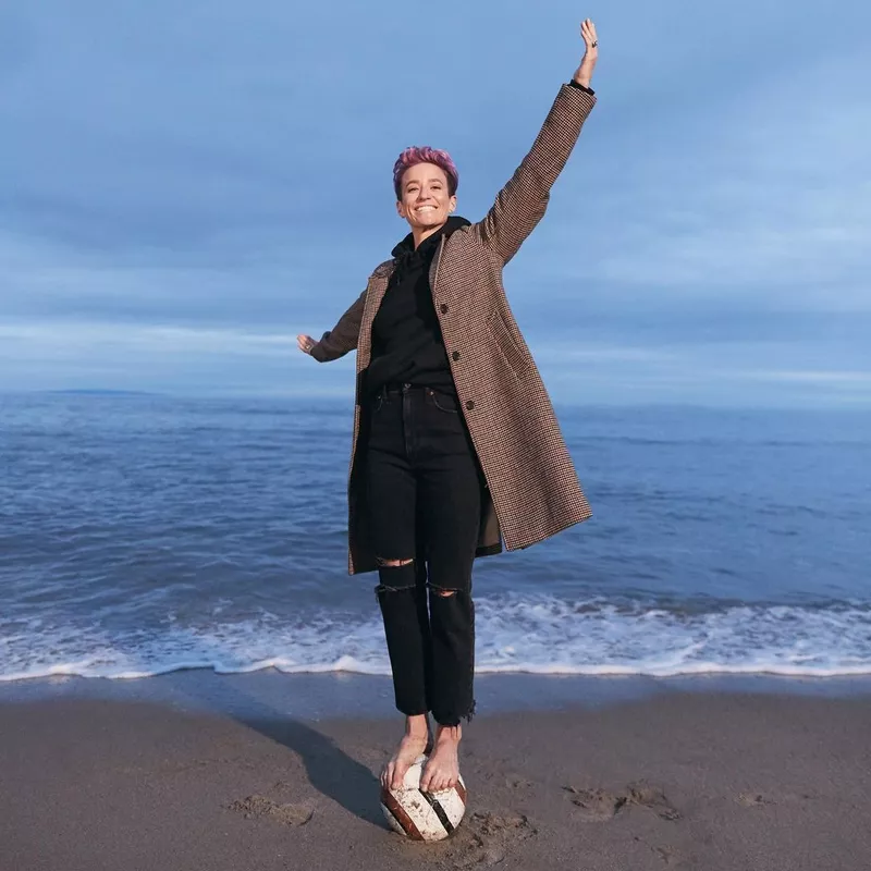 Megan Rapinoe standing on a soccer ball