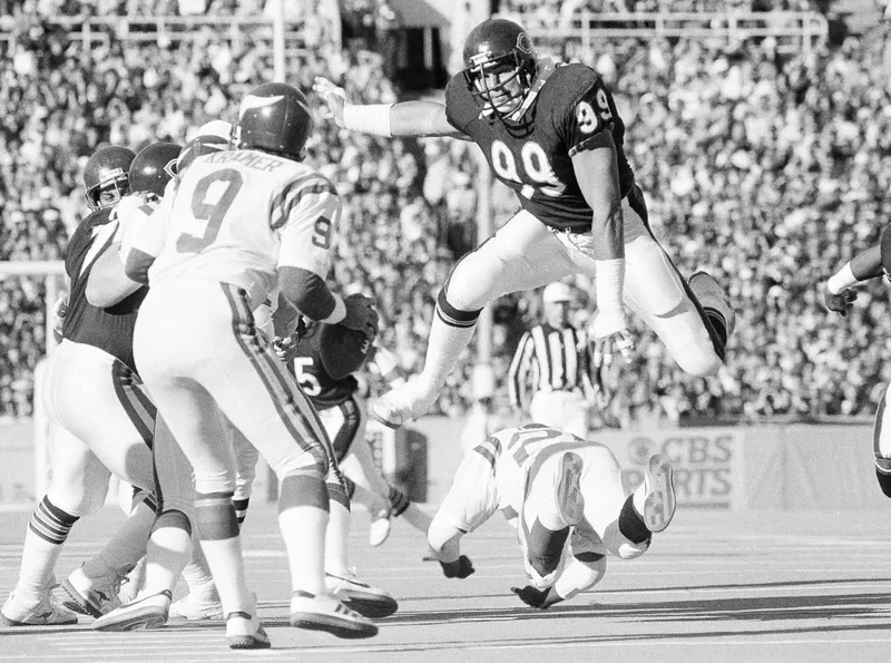 Chicago Bears tackle Dan Hampton leaps over player