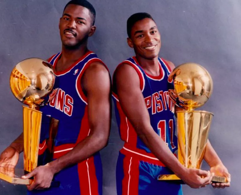 Joe Dumars and Isiah Thomas posing with trophies