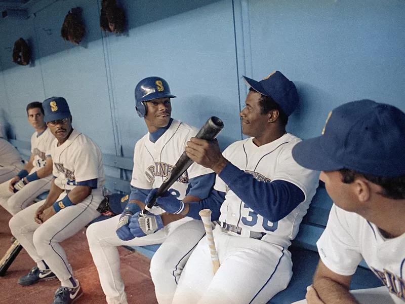 Ken Griffey, Jr., and Ken Griffey, Sr., kid around on bench