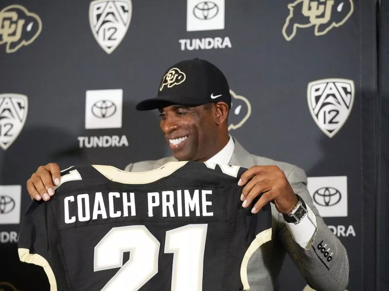 Colorado head coach Deion Sanders holds up Coach Prime jersey