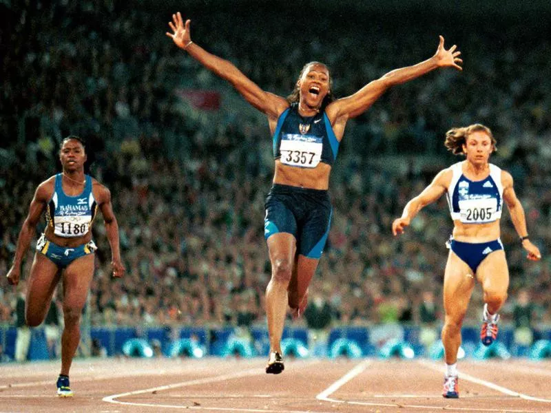 Marion Jones celebrates after crossing finish