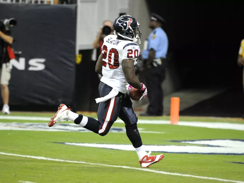 Steve Slaton rushes by Oakland Raiders' Tyvon Branch