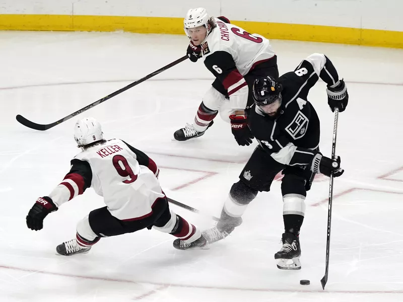 Los Angeles Kings defenseman Drew Doughty skates around Arizona Coyotes' Clayton Keller and Jakob Chychrun