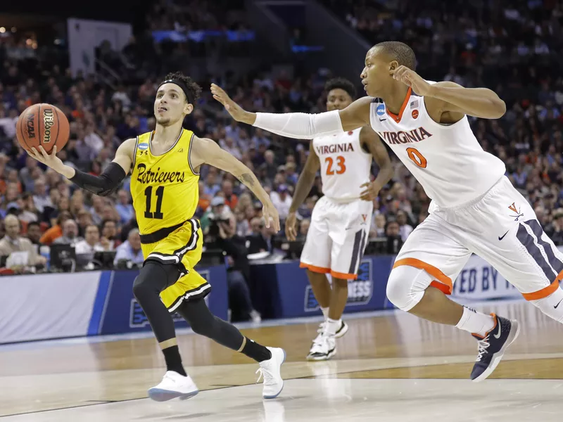 UMBC's K.J. Maura drives past Virginia's Devon Hall