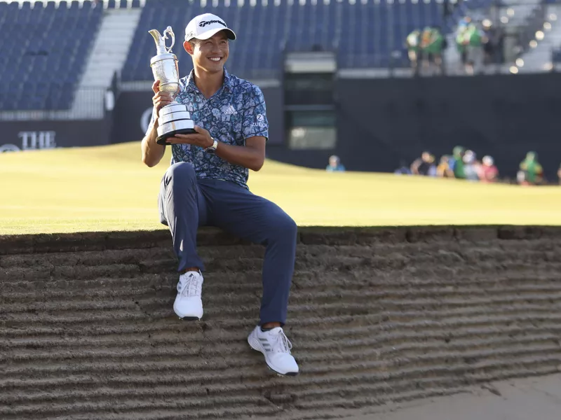 Collin Morikawa holds up claret jug trophy