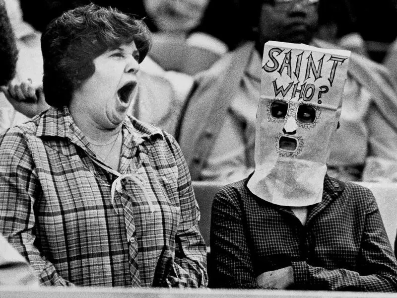 A spectator yawns while another wears bag over head