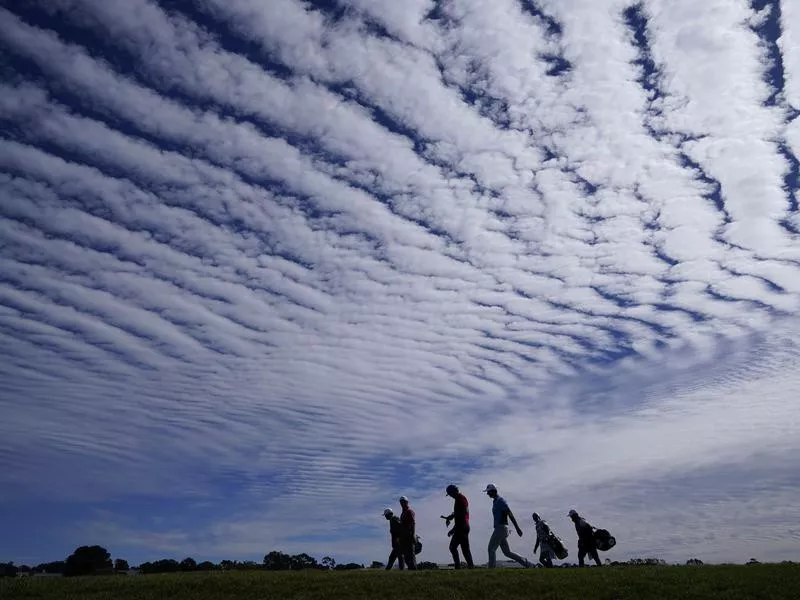 Jon Rahm,Adam Scott,and Viktor Hovland walk on sixth fairway