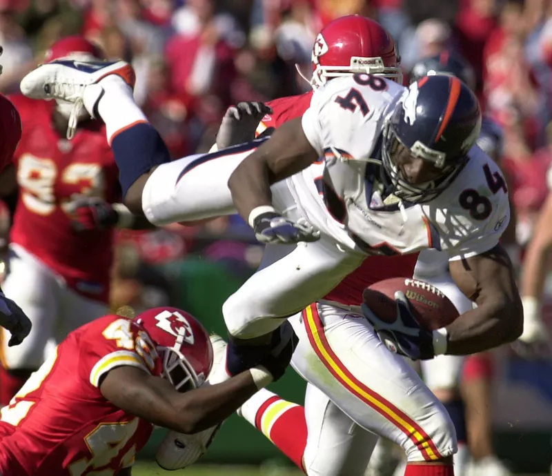 Denver Broncos tight end Shannon Sharpe diving over Kansas City Chiefs safety Shaunard Harts