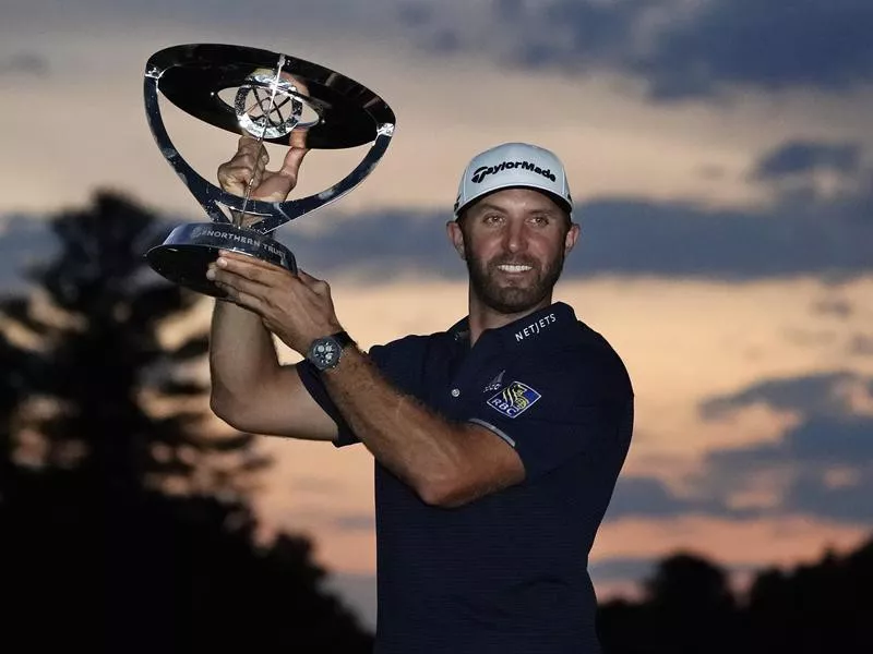 Dustin Johnson holds trophy