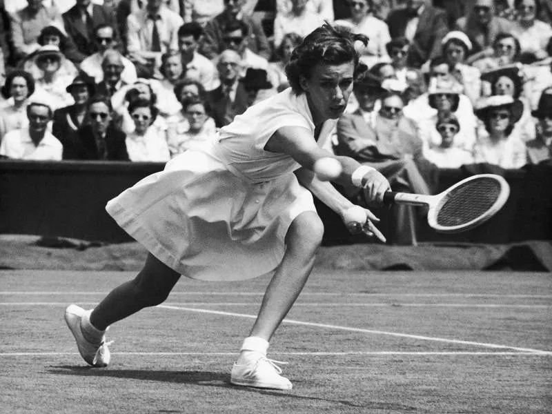 Women's tennis player Doris Hart reaches for a backhand