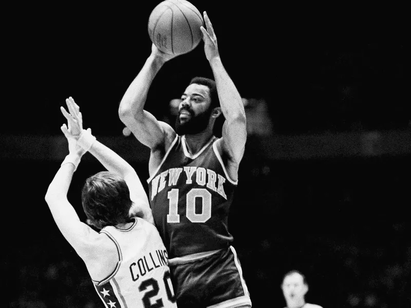 Walt Frazier goes up over 76ers guard Doug Collins