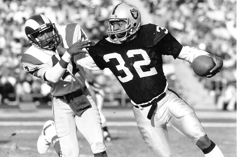 Los Angeles Raiders running back Marcus Allen fends off Los Angeles Rams cornerback LeRoy Irvin